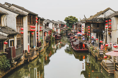 Canal amidst houses against sky in city