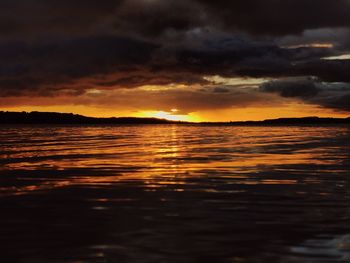 Scenic view of sea against dramatic sky during sunset
