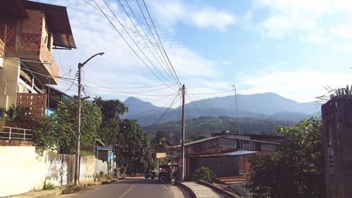 Road by houses against sky