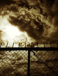 Barbed wire fence against cloudy sky