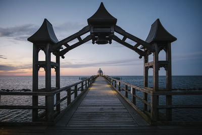 Pier over sea against sky during sunset