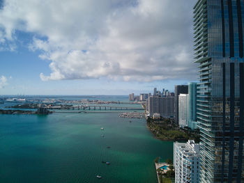 Sea by modern buildings against sky in city