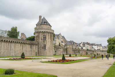 Buildings in garden against cloudy sky