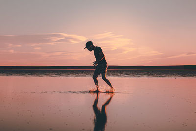 Man standing on beach against sky during sunset