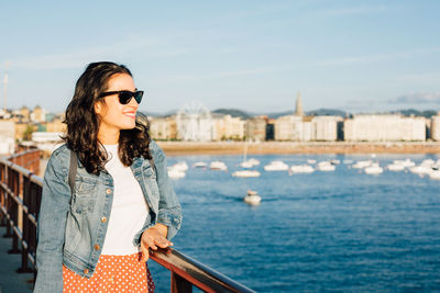 Young woman wearing sunglasses standing against sky