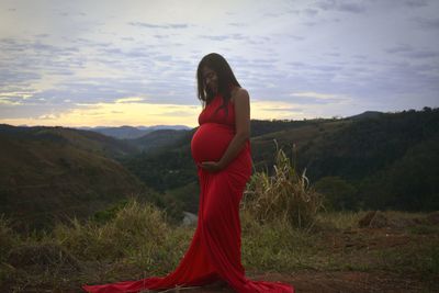 Young woman standing on rock against sky