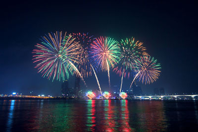 Low angle view of firework display over river at night