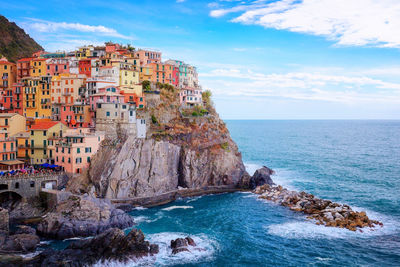 Residential buildings on cliff by sea against cloudy sky