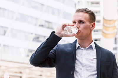 Businessman drinking water while standing outdoors