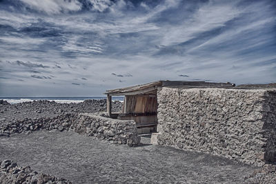 Exterior of abandoned building by sea against sky