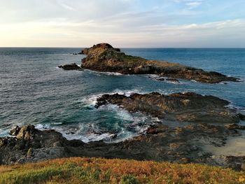 Scenic view of rocks on sea against sky