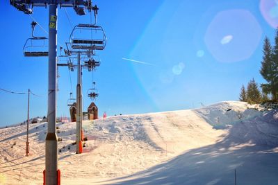 Ski lift over snowcapped mountains against sky