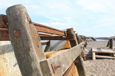 Rusty metallic structure on beach against sky