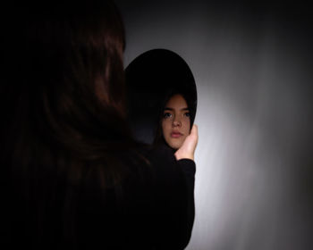 Portrait of woman standing against black background