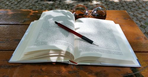 High angle view of book and pen by sunglasses on table