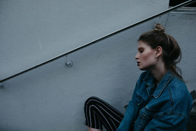 Thoughtful woman wearing denim jacket while sitting outdoors