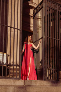 Low angle view of woman in pink evening gown standing at doorway