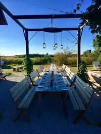 Empty chairs by swimming pool against clear blue sky