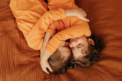 Happy children brother and sister in pajamas lying on the bed in interior of the bedroom of  house