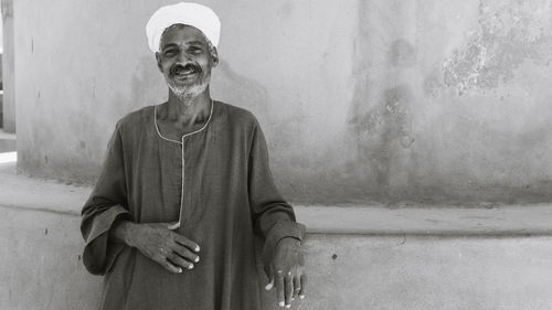 Portrait of smiling man standing against wall