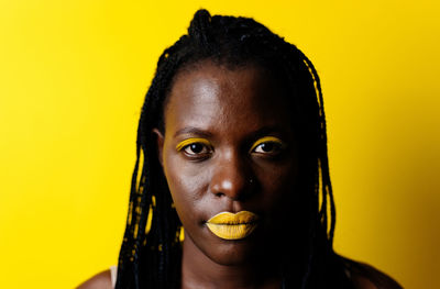 Close-up portrait of woman against yellow background