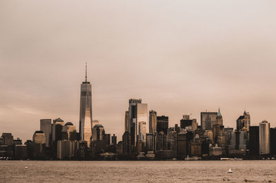 Sea by modern buildings against sky in city