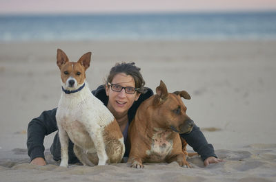 Portrait of woman with dogs at beach during sunset