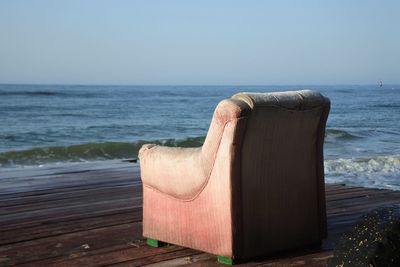 Low section of man relaxing on beach against clear sky