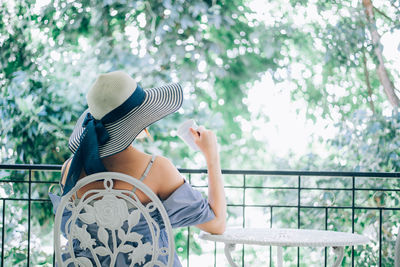 Midsection of woman holding umbrella against trees