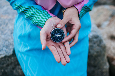 Midsection of woman holding navigational compass at beach against sky