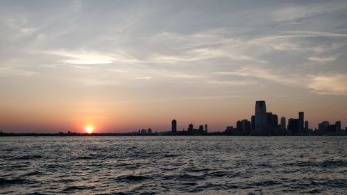 Scenic view of sea and buildings against sky during sunset