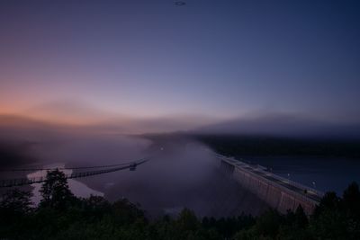 Bridge over river against sky at sunset