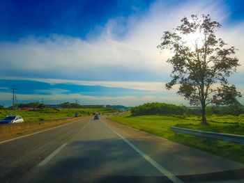 Road by trees against sky