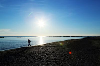 Man on beach against sky during sunset