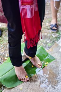 Low section of woman standing on wet banana leaf