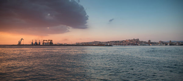 Scenic view of sea and buildings against sky at sunset