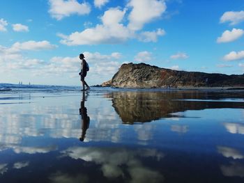 Man walking at beach against sky