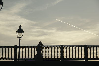 Silhouette man standing by railing against sky