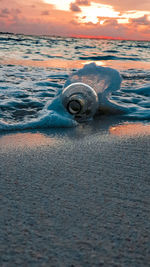 Surface level of sea shore against sunset sky