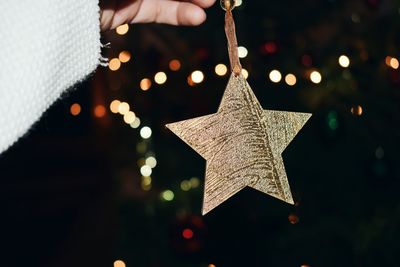 Close-up of hand holding illuminated christmas tree at night