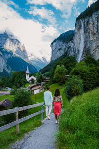 Rear view of people walking on mountain against sky
