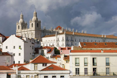 Monastery of sao vicente de fora by buildings against cloudy sky