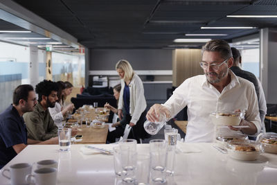 Man pouring water during lunch break in office