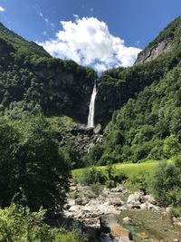 Scenic view of waterfall in forest against sky