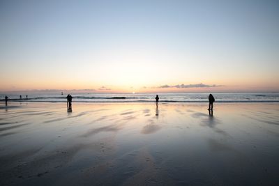 Silhouette person standing on beach against clear sky during sunset