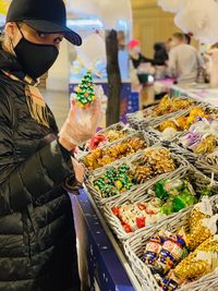 Midsection of woman holding toys  for sale at market stall