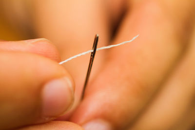 Close-up of hand threading needle 