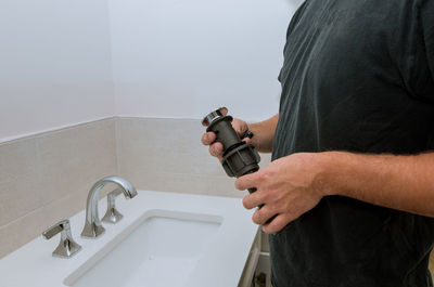 Midsection of plumber working in bathroom