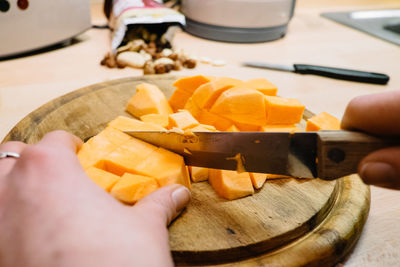 Cropped image of hands chopping pumpkins on cutting board