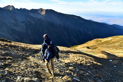 Rear view of man on mountain against sky